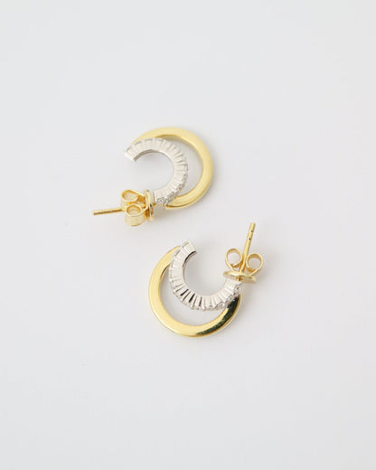 Pair of gold and silver moon-shaped earrings on a light gray background