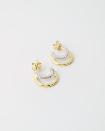 Pair of gold and silver earrings on a light gray background