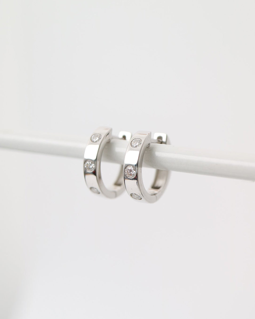 Silver hoop earrings with small diamonds on a white background