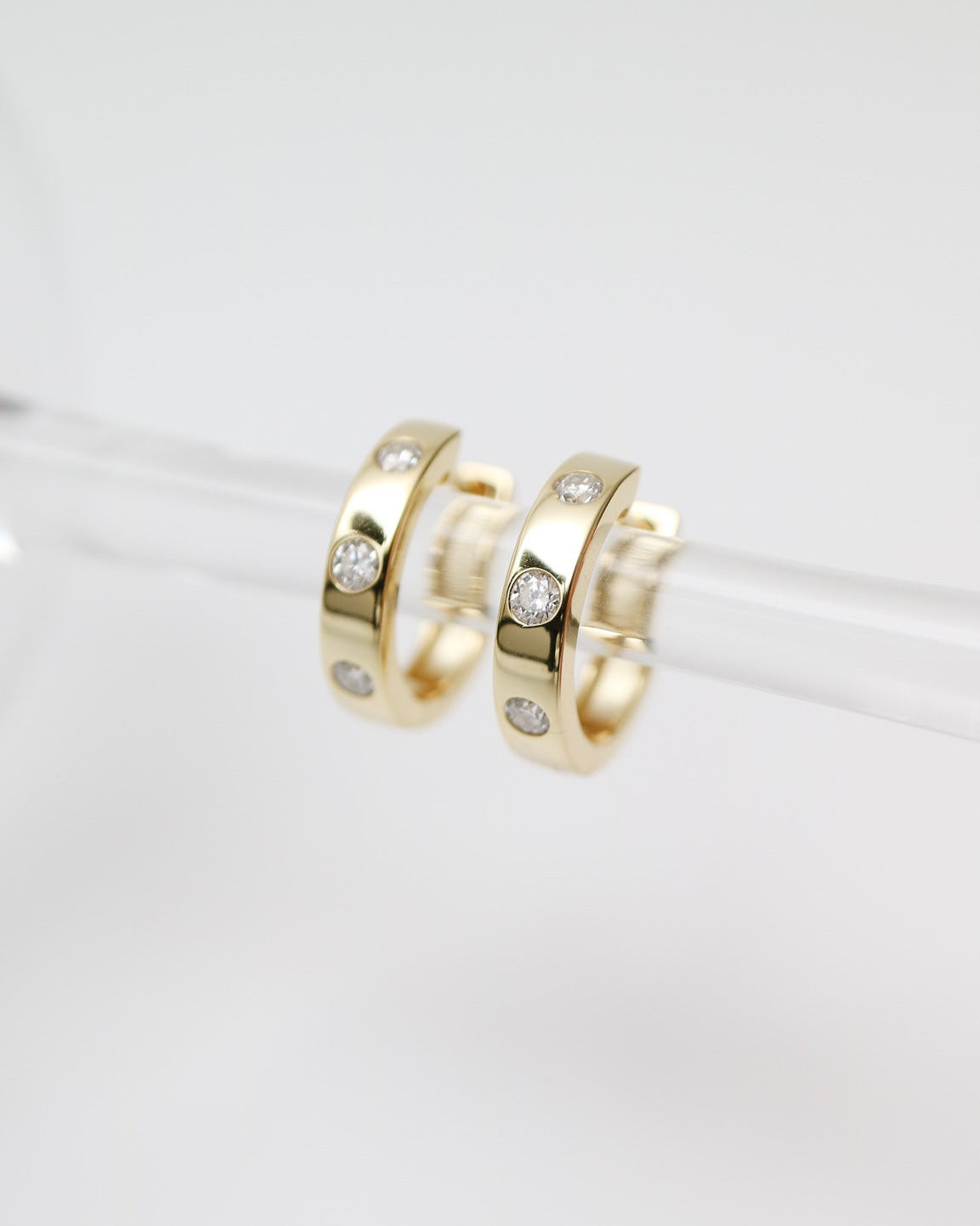 Gold hoop earrings with embedded stones on a white background