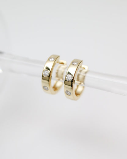 Gold hoop earrings with embedded stones on a white background