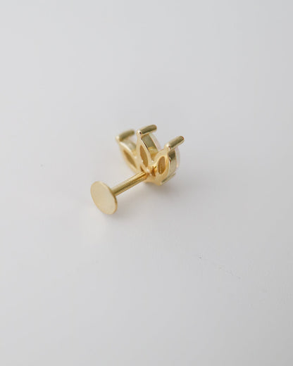 A single gold stud earring shown from the side on a clean, light gray background.