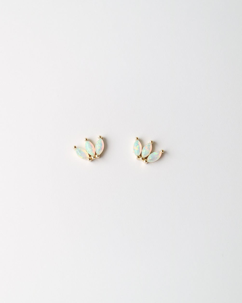 A pair of small gold-toned stud earrings with iridescent pale blue-green opal inlays, shown on a plain white background.