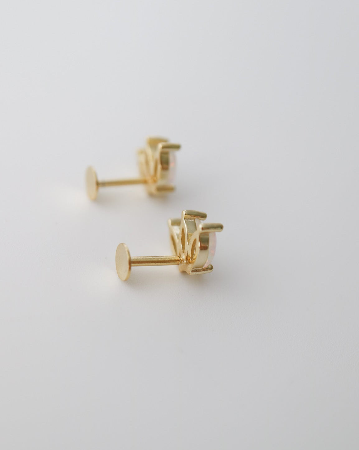 A pair of gold stud earrings with a geometric, multi-pronged setting, displayed on a clean white surface.