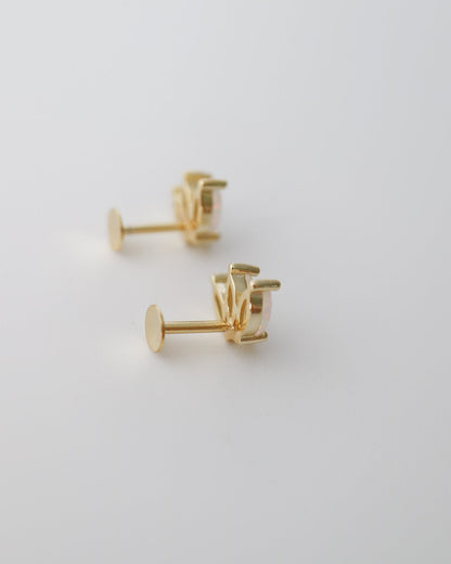 A pair of gold stud earrings with a geometric, multi-pronged setting, displayed on a clean white surface.