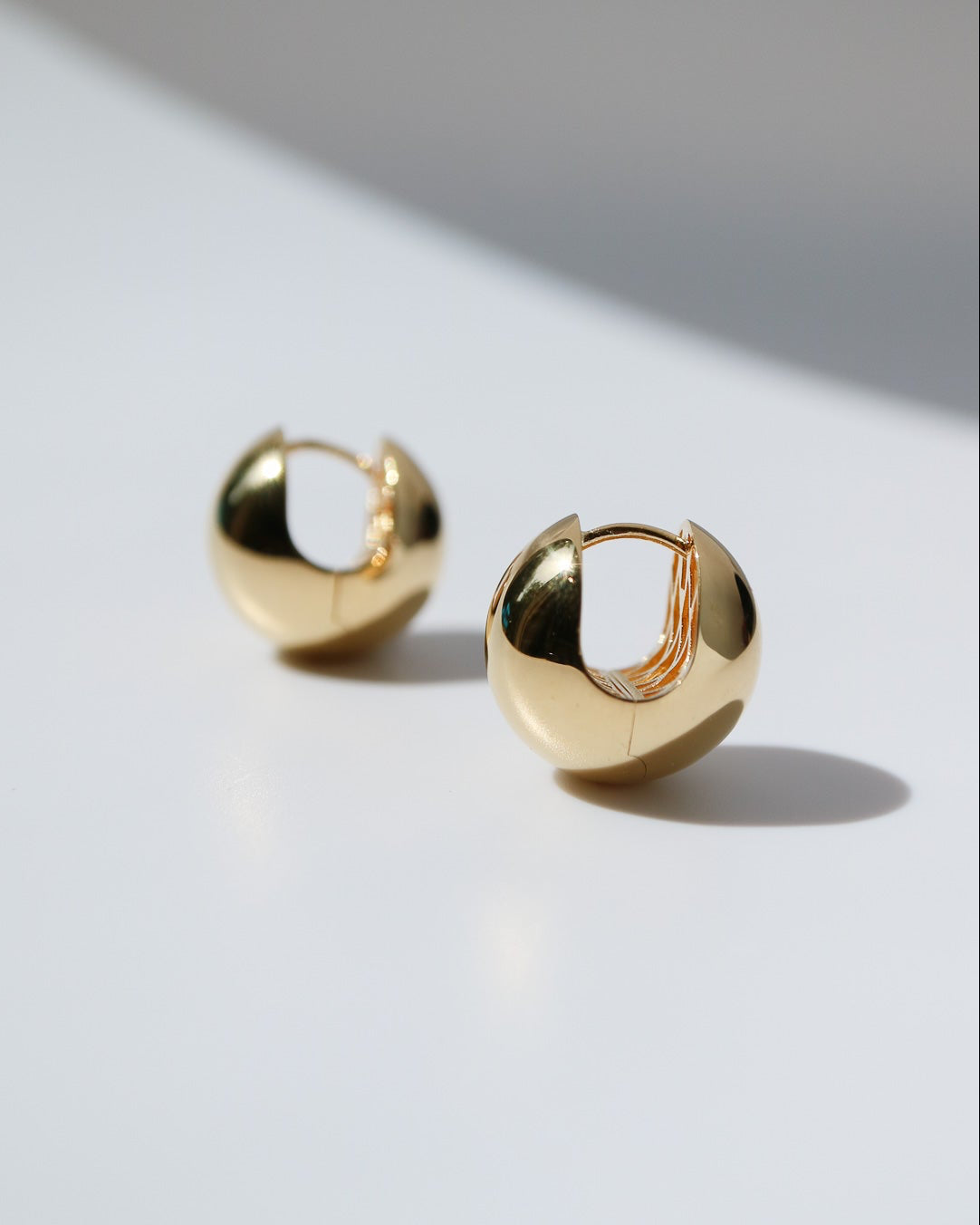 Pair of polished 9ct yellow gold Orbit Huggie earrings with a chunky rounded silhouette and secure hinged fastening.