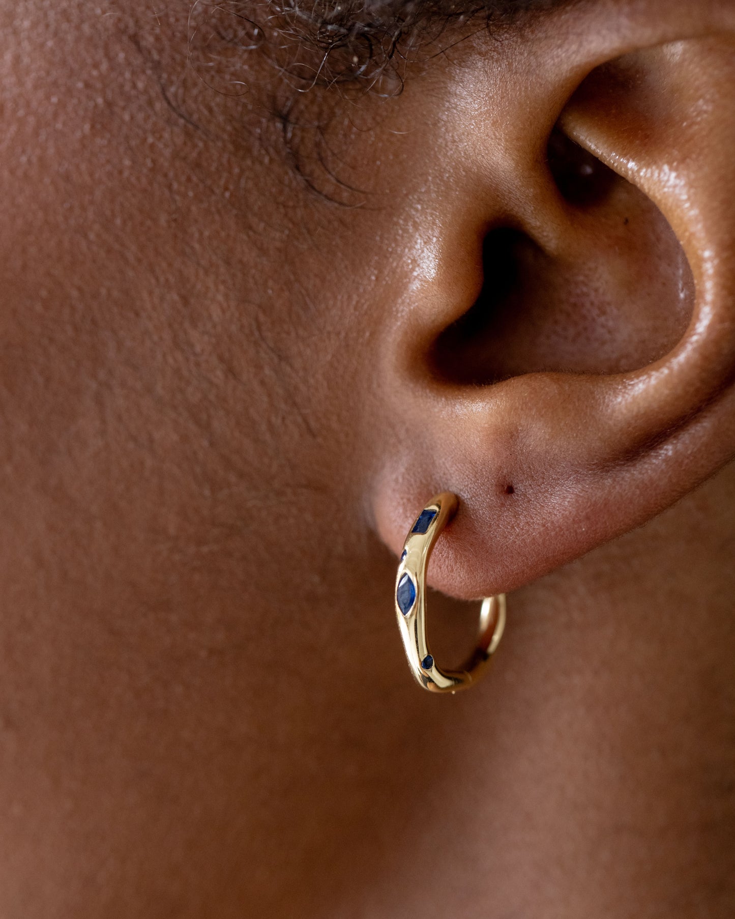 Gold hoop earrings on brown skinned model