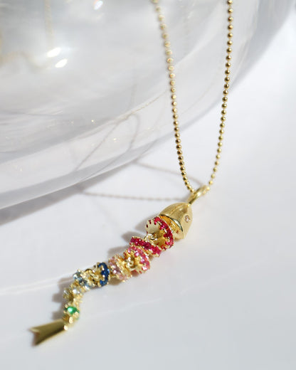 Colorful fish-shaped pendant on a gold chain against a white background