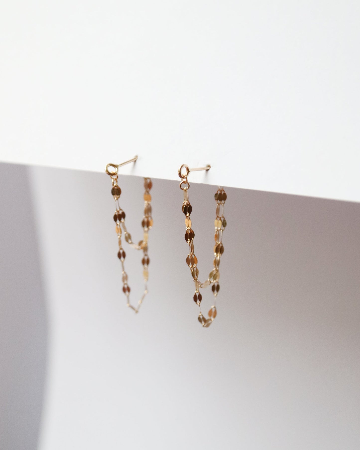 Pair of beaded earrings on a white surface with a light background