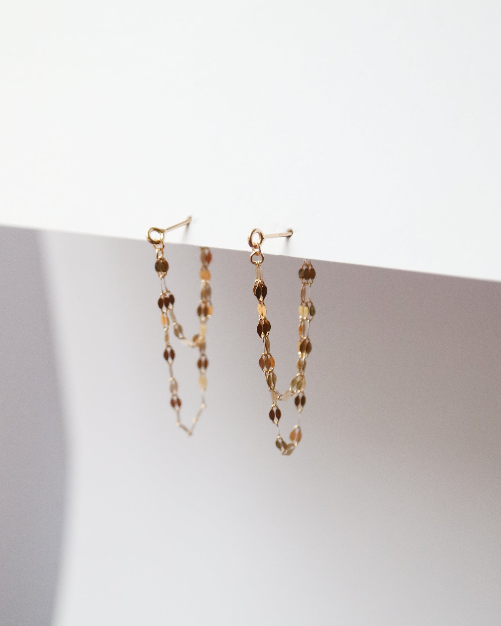 Pair of beaded earrings on a white surface with a light background