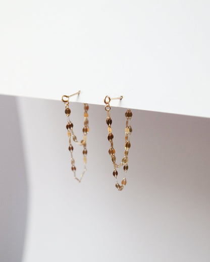 Pair of beaded earrings on a white surface with a light background