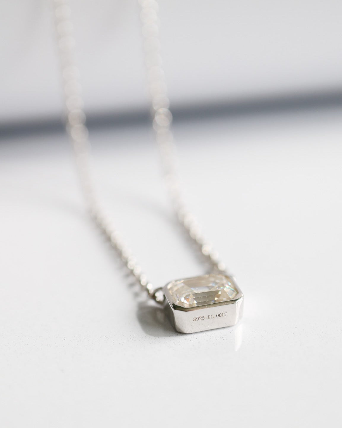 Silver necklace with a square pendant on a white background