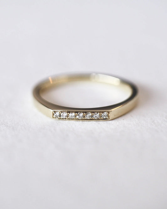 Gold ring with small diamonds on a light gray background