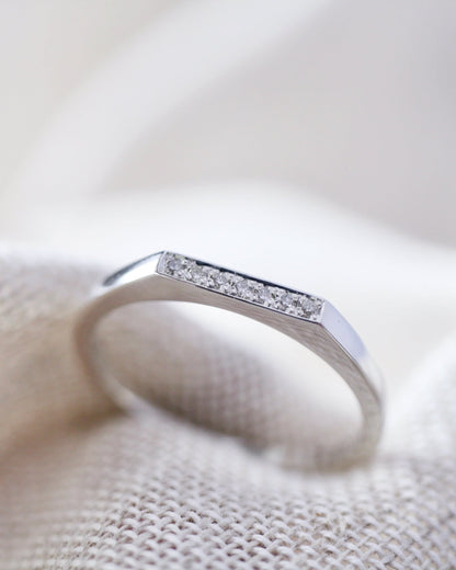 Silver ring with small diamonds on a textured beige surface