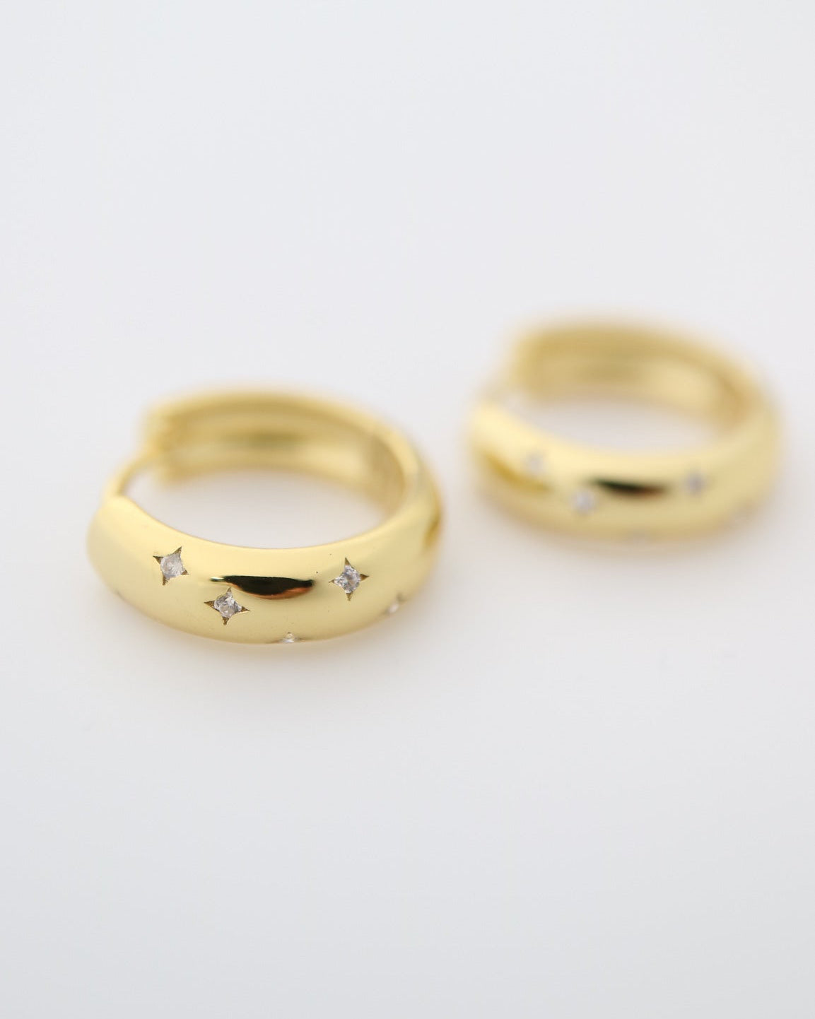 Gold plated sterling silver Solstice Huggie earrings featuring star-inspired cubic zirconia accents and a polished hinged hoop design.