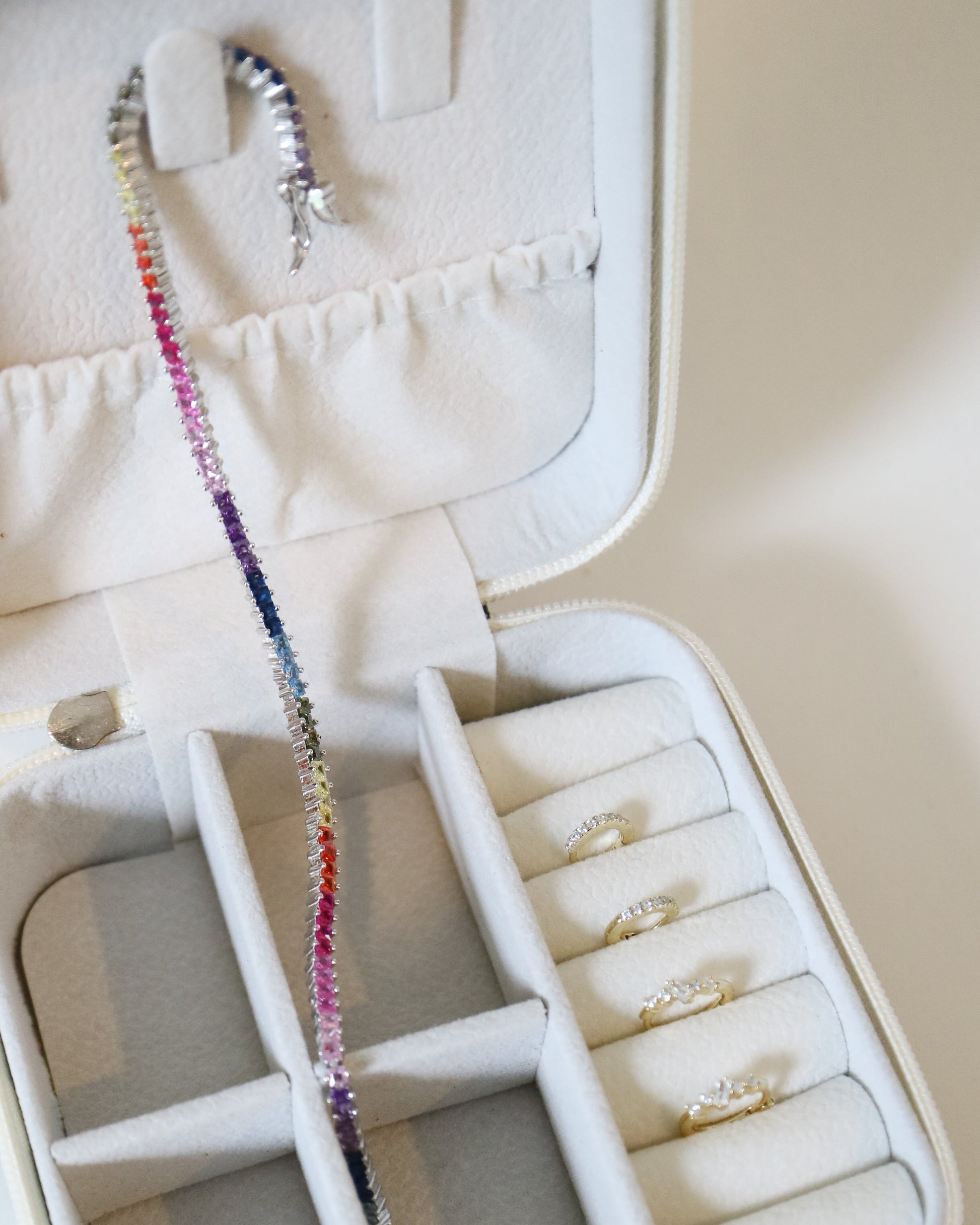 Jewelry case with a colorful beaded necklace and rings on a white background