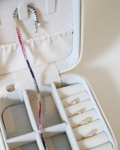 Jewelry case with a colorful beaded necklace and rings on a white background