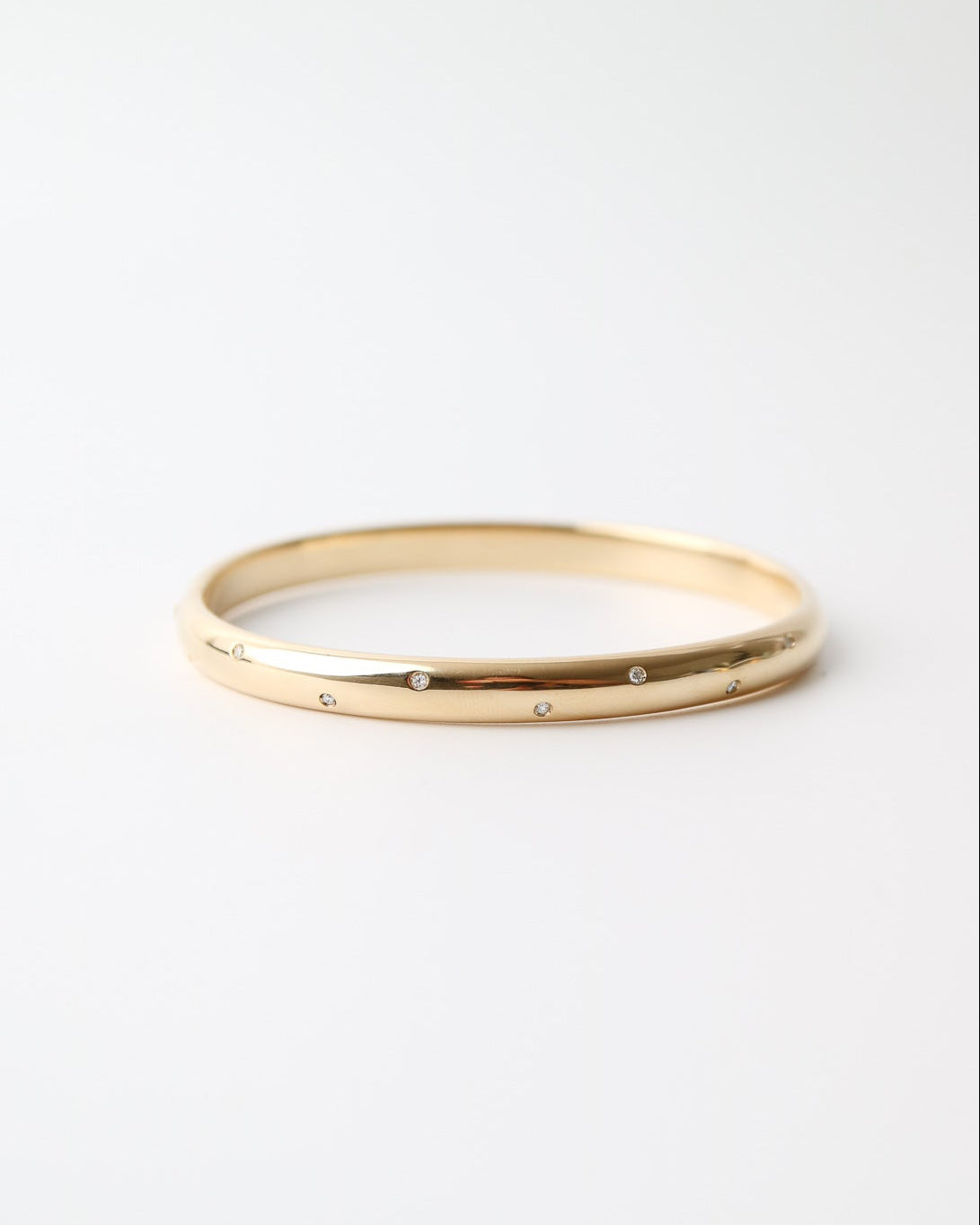 9ct yellow gold bangle with scattered lab-grown diamonds and a polished finish on a white background.