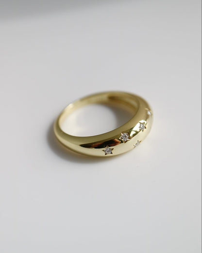Gold ring with embedded stones on a light gray background