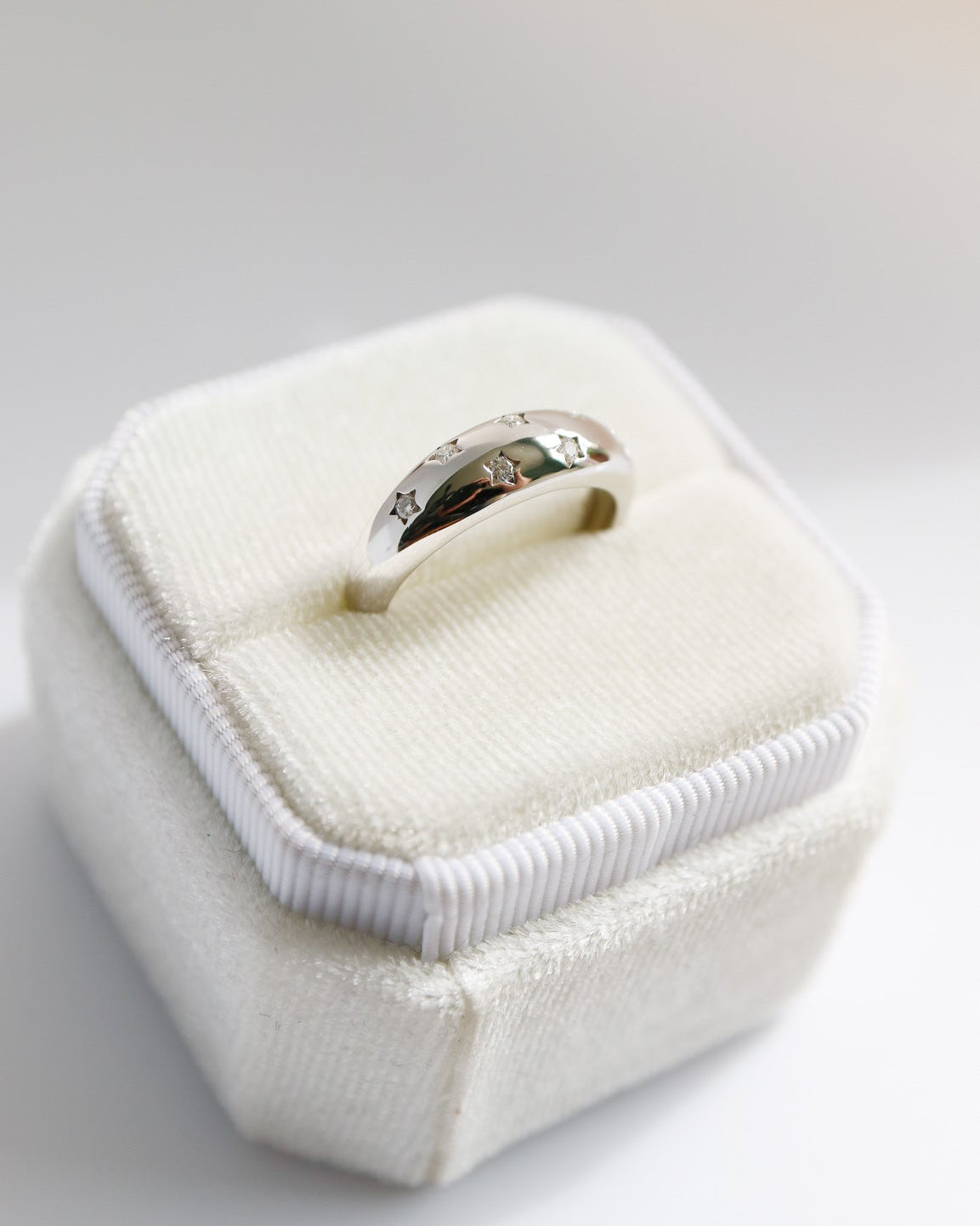Silver ring in a white jewelry box on a light gray background