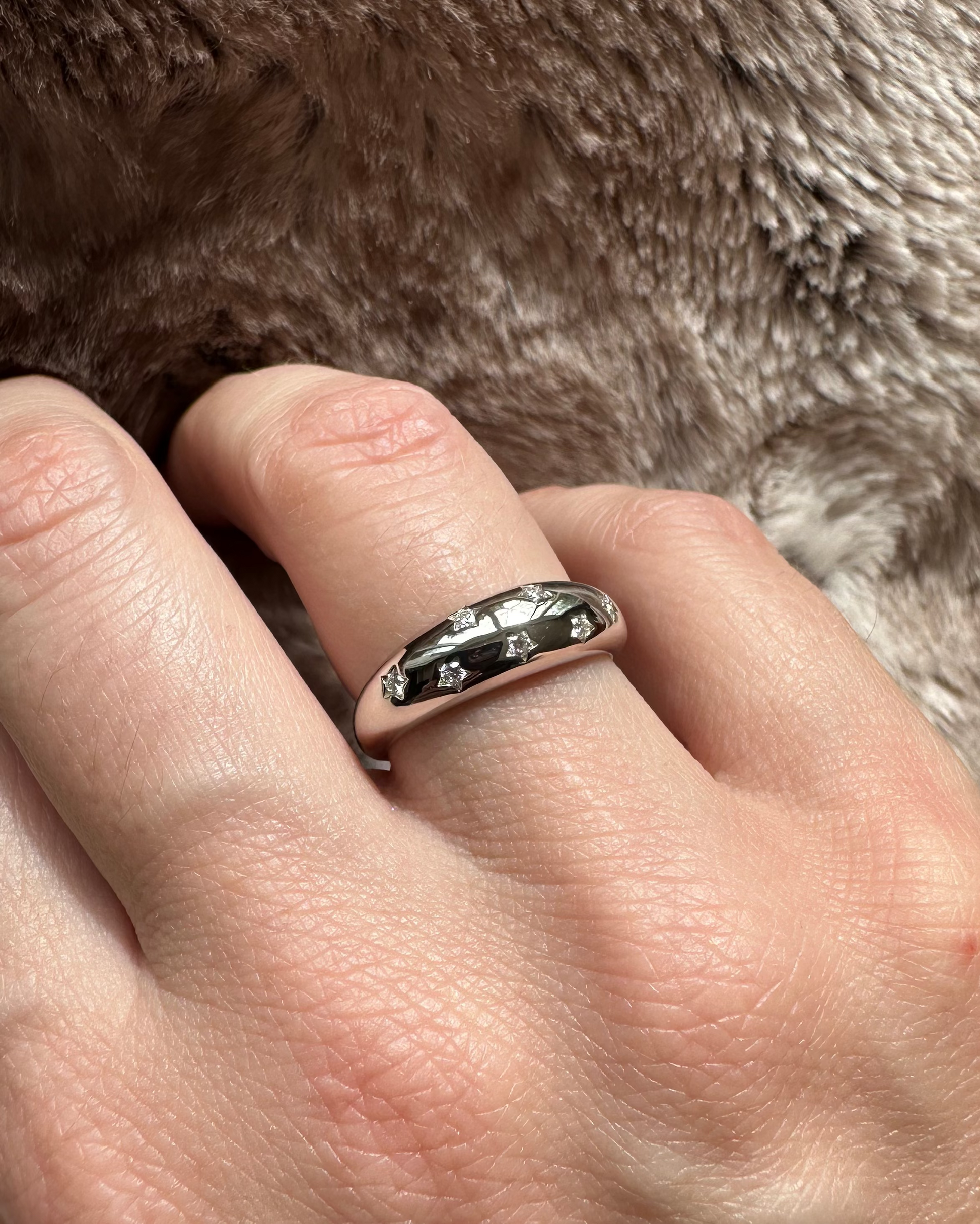 Hand wearing a ring with a fur background
