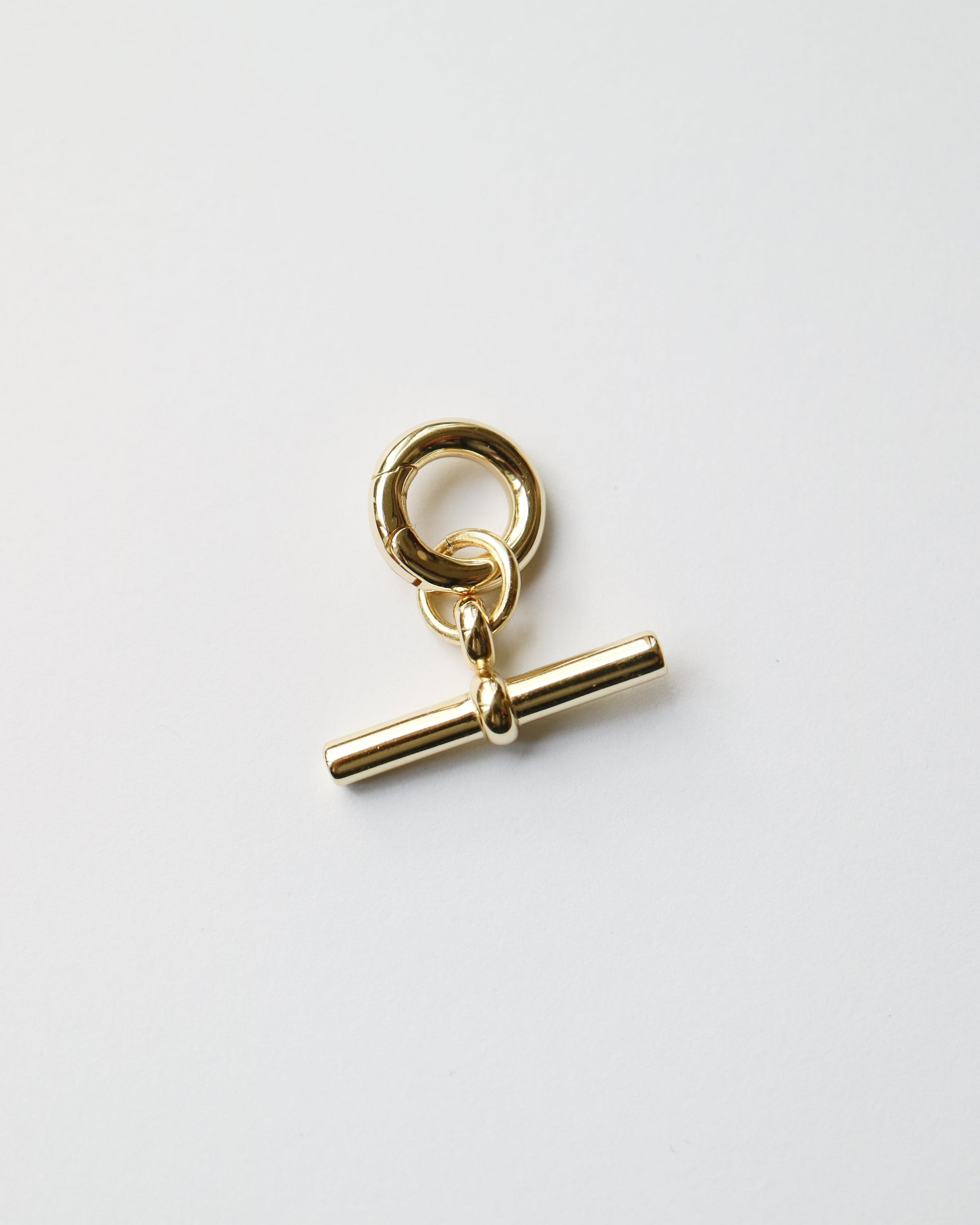 Gold charm with a bar and ring on a white background