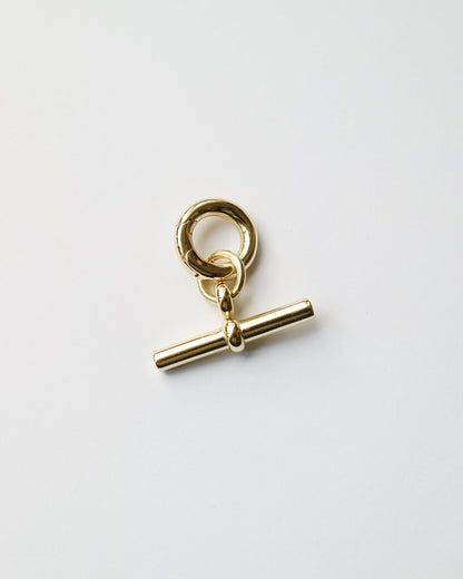 Gold charm with a bar and ring on a white background