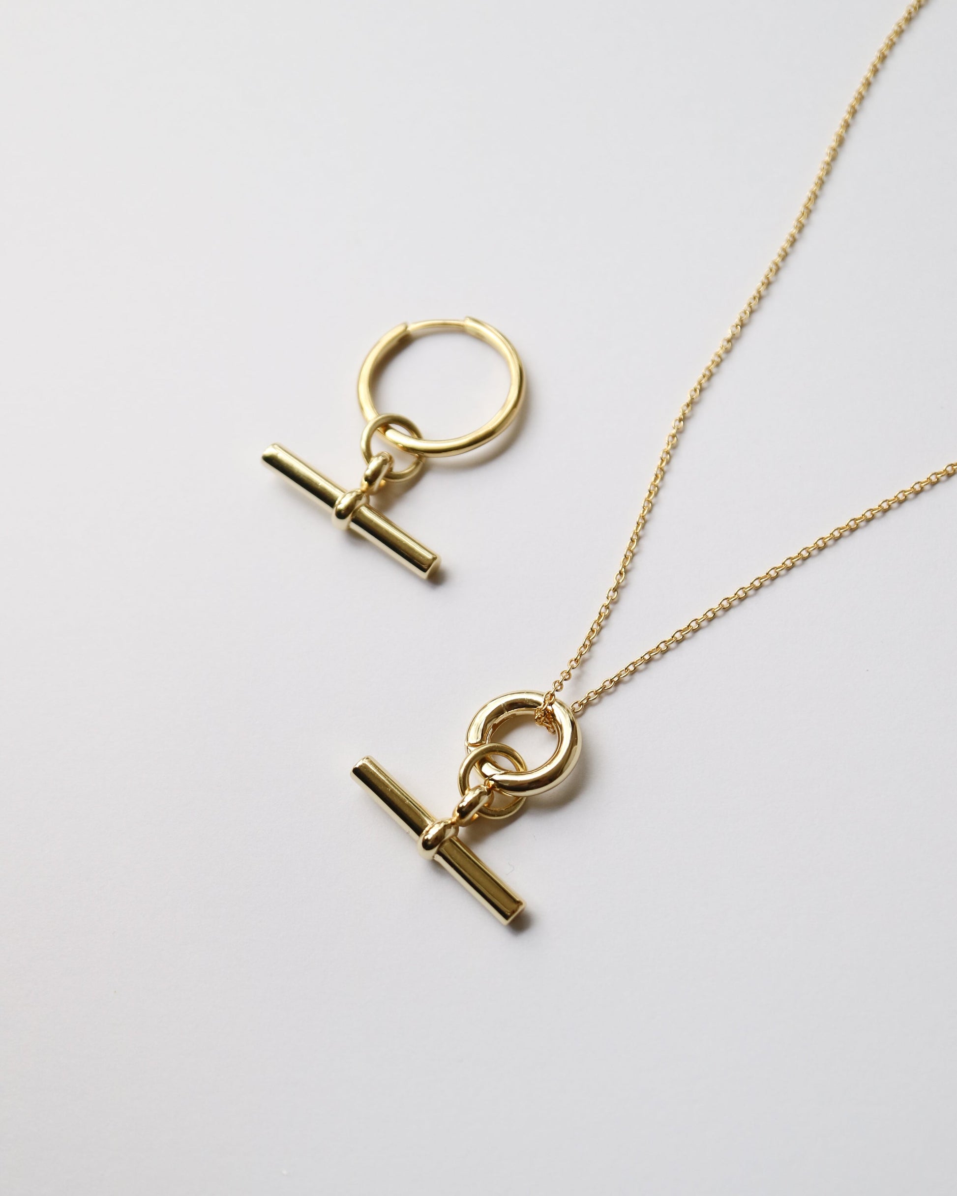 Gold necklace with pendant on a light gray background