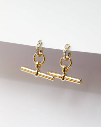 Gold earrings with a minimalist design on a light gray background