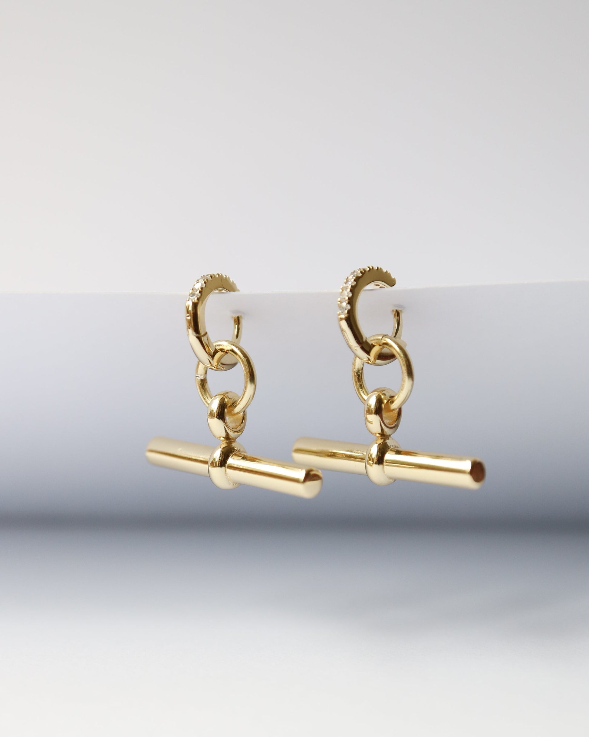 Gold earrings on a light gray background