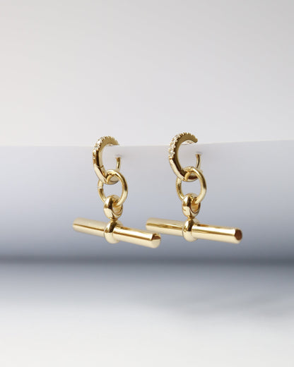 Gold earrings on a light gray background