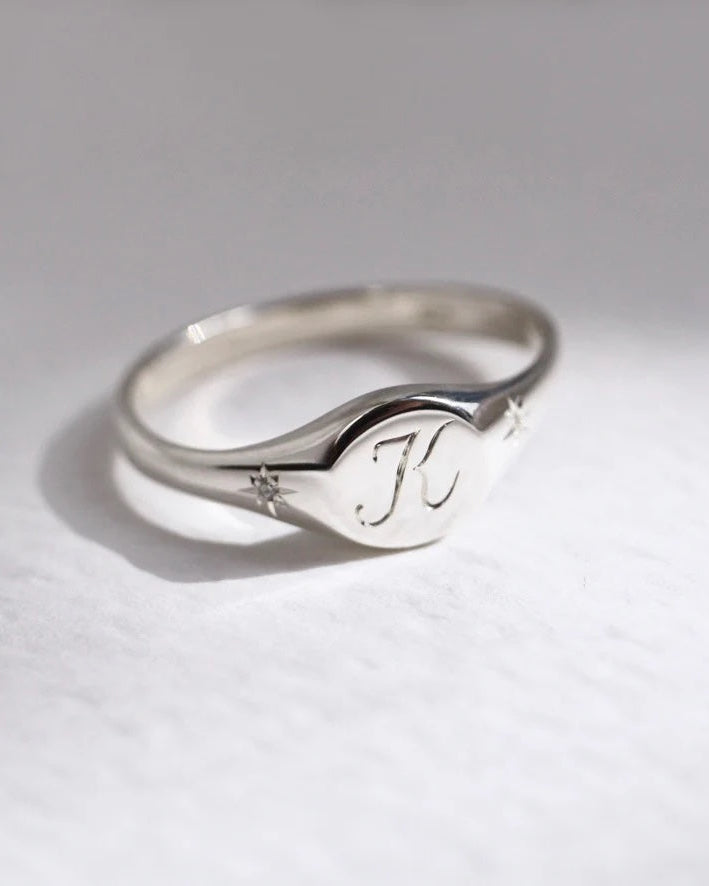 Silver ring with engraved initials on a light gray background