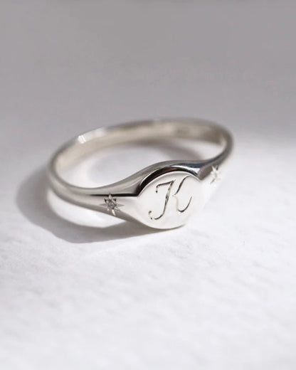 Silver ring with engraved initials on a light gray background