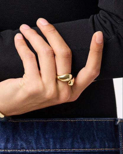 Hand wearing a gold ring with a blurred background