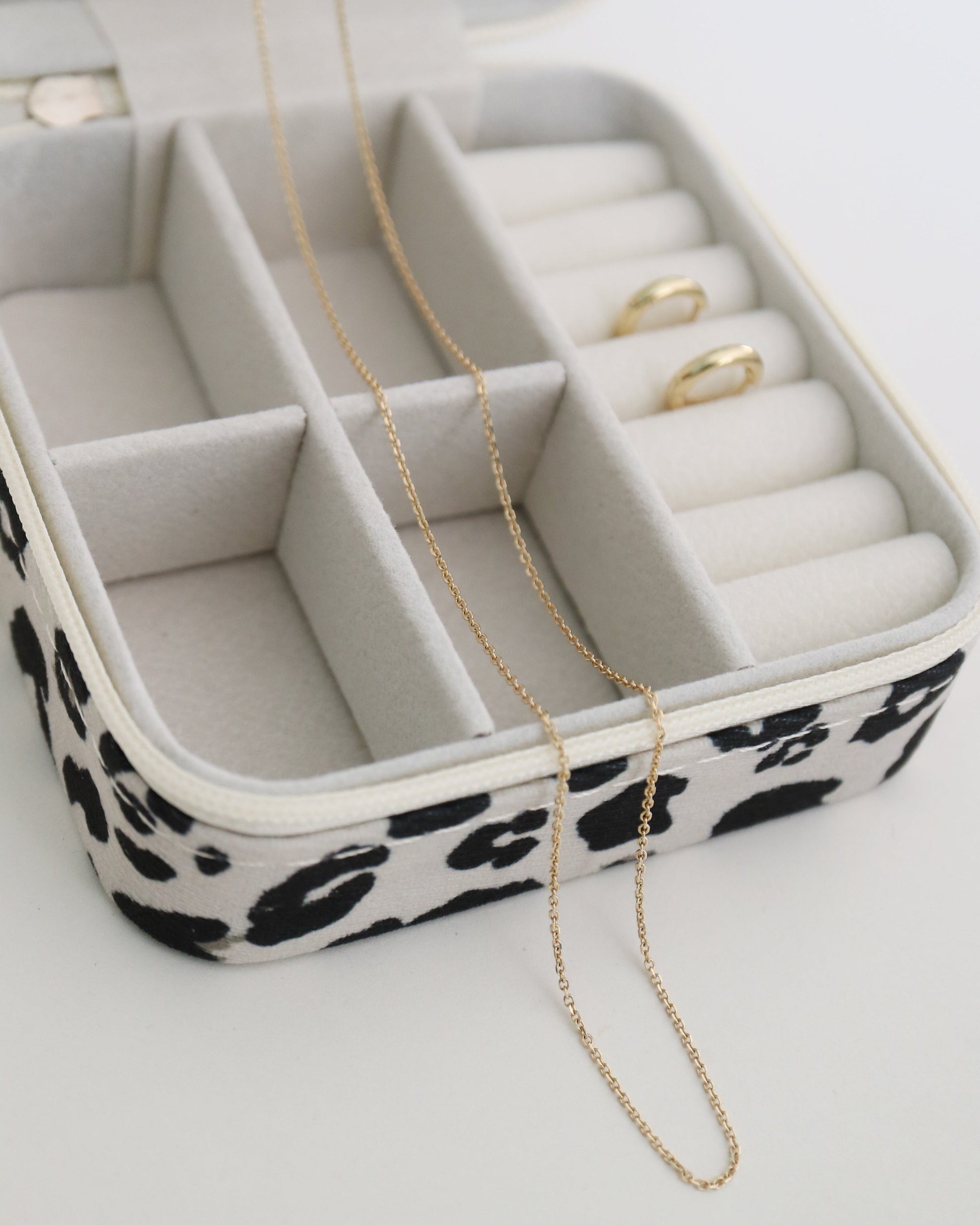 Jewelry box with leopard print base containing jewelry on a white background