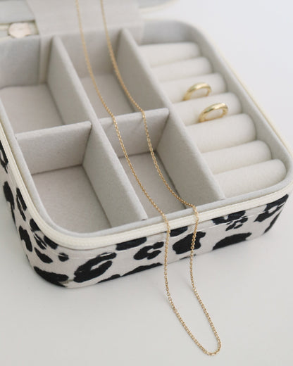 Jewelry box with leopard print base containing jewelry on a white background