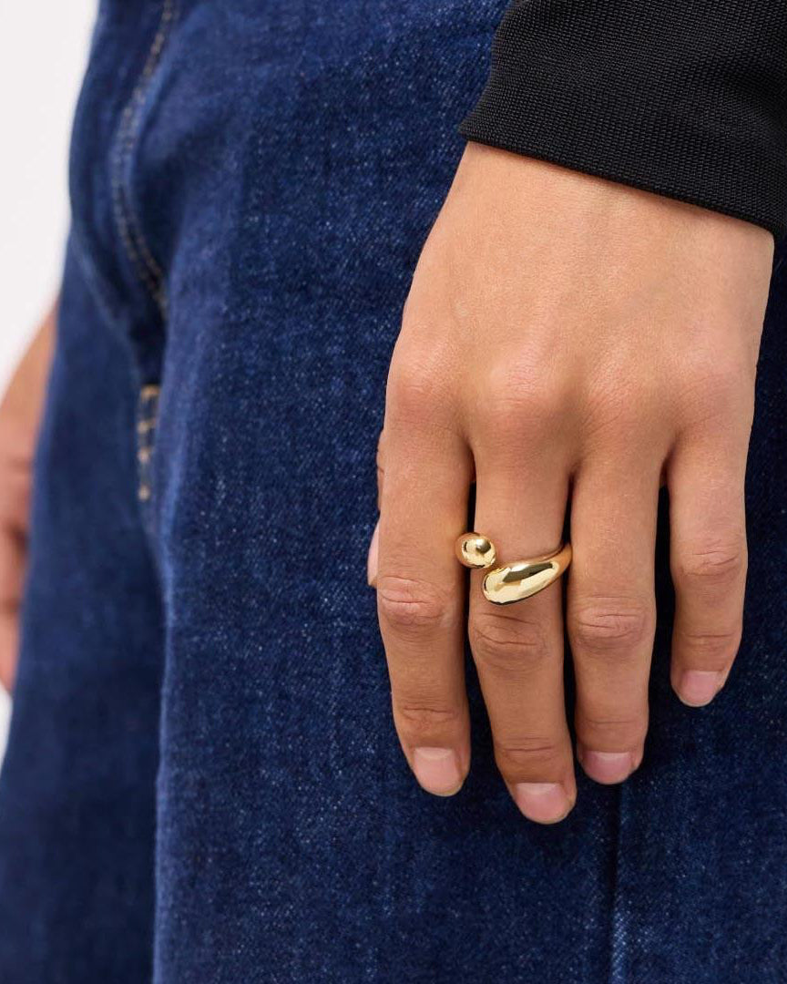 Hand wearing a gold ring on a blue denim background