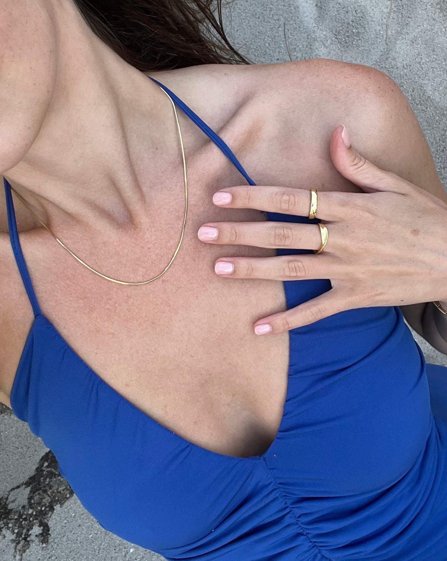Person wearing a blue dress with a close-up of the neckline and hand.