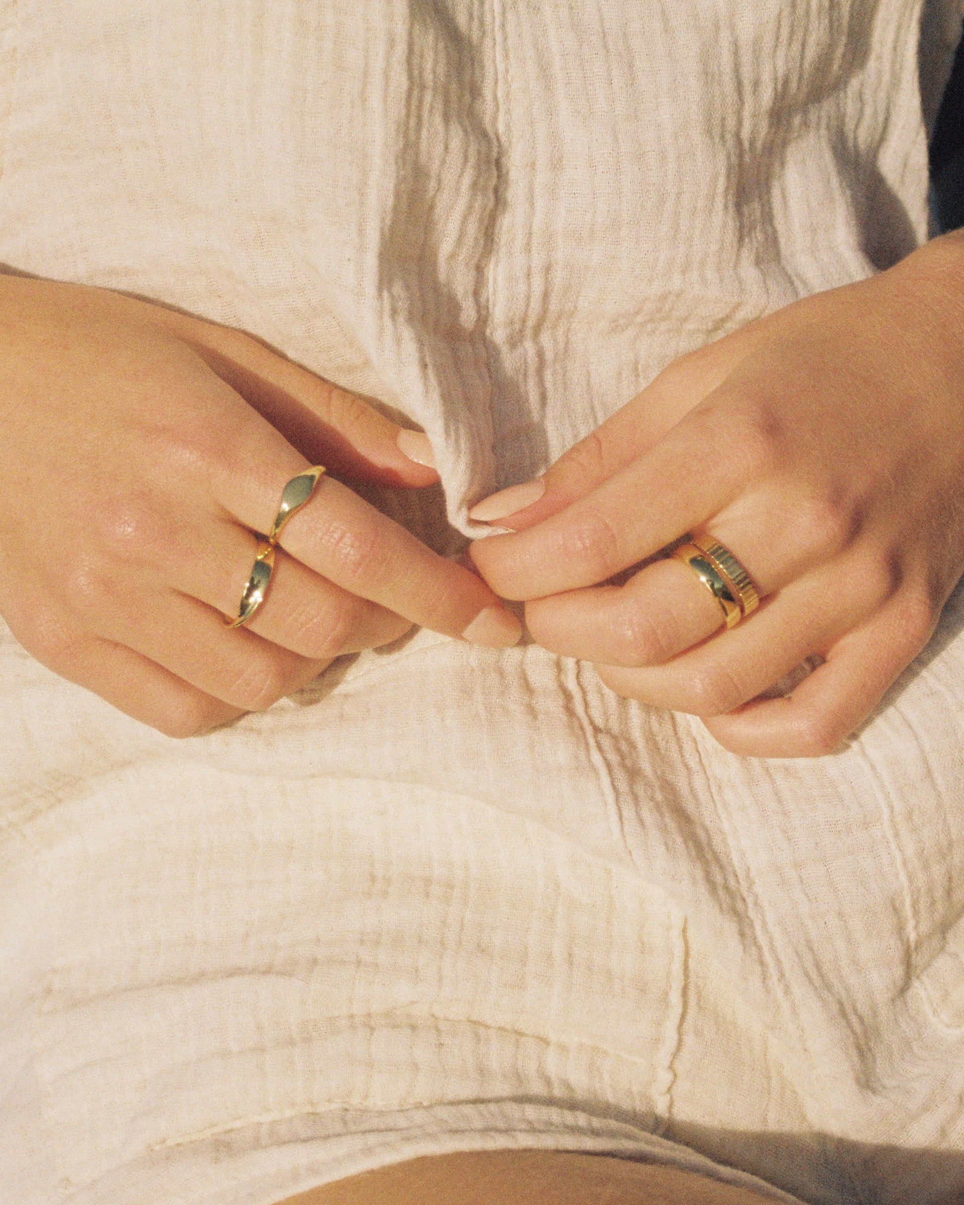 Close-up of hands with rings on a textured fabric background