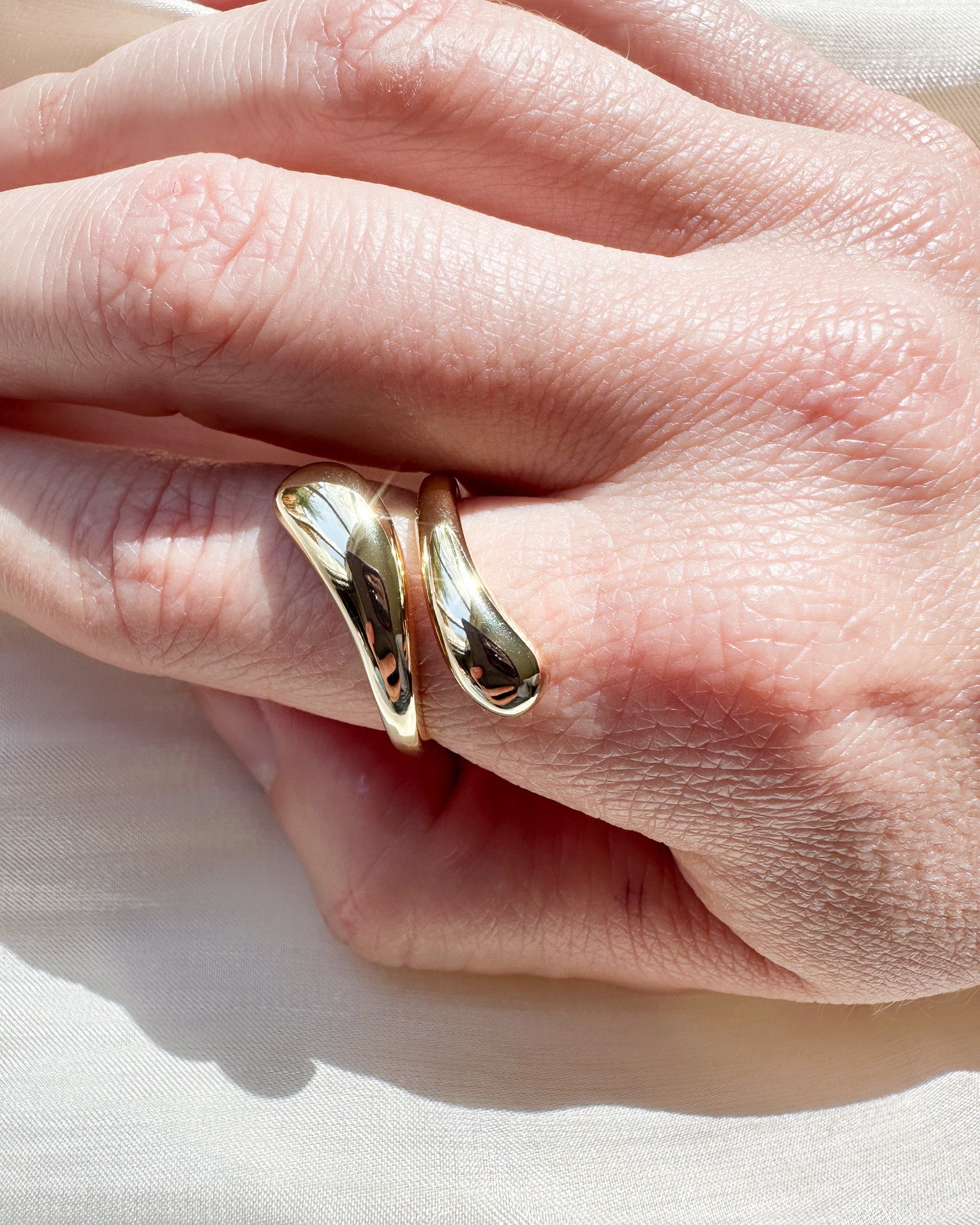 Gold ring on a person's finger with a light background