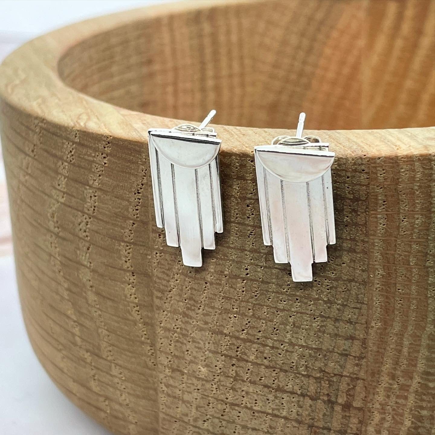 Silver earrings close up on wooden bowl