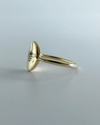 9ct gold oval ring with bee engraving, shown from the side on white background