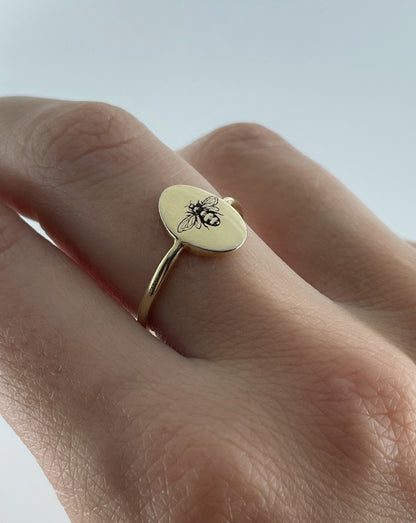 9ct gold oval ring with bee engraving, shown on female hand