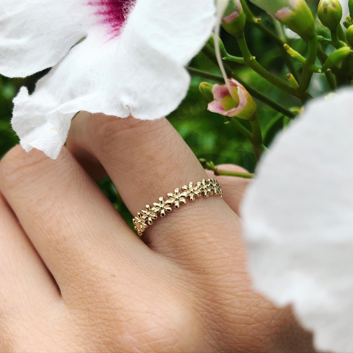 Solid gold ring with flower motif, shown on hand