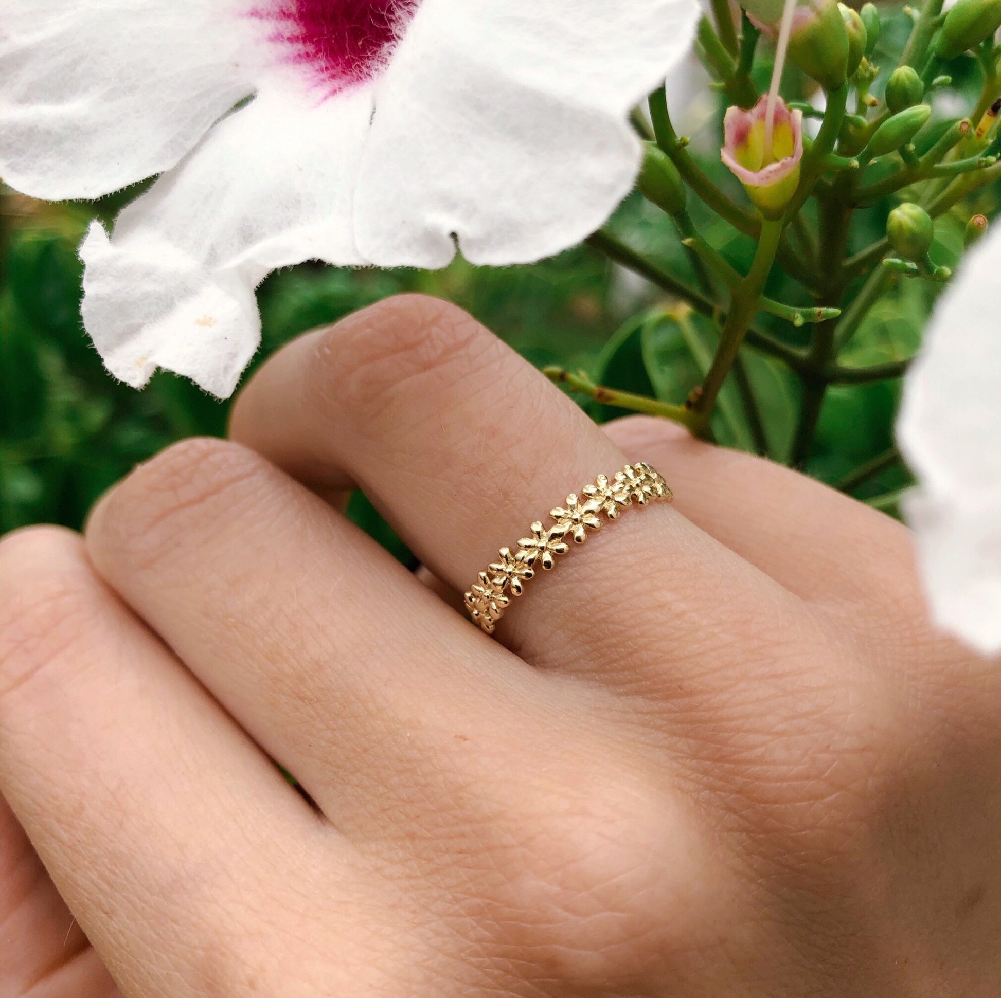 Solid gold ring with flower motif, displayed on hand