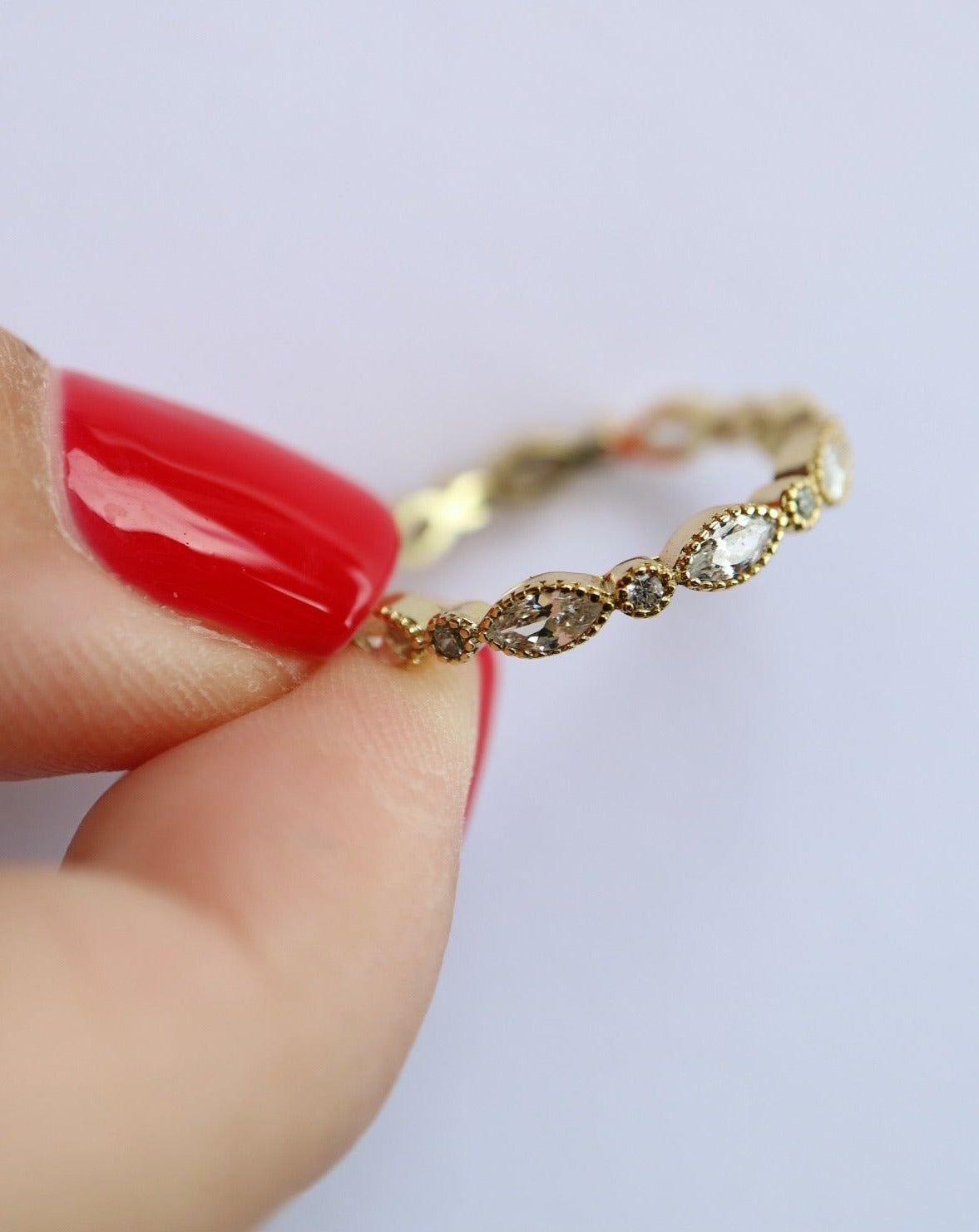 Gold ring in female hand with red nails