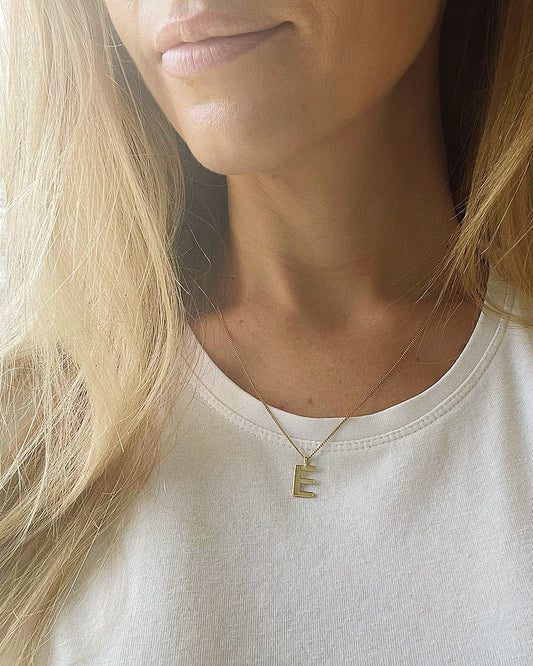 Collective & Co. Initial in solid gold on gold chain, shown on neck of blond woman in white t-shirt