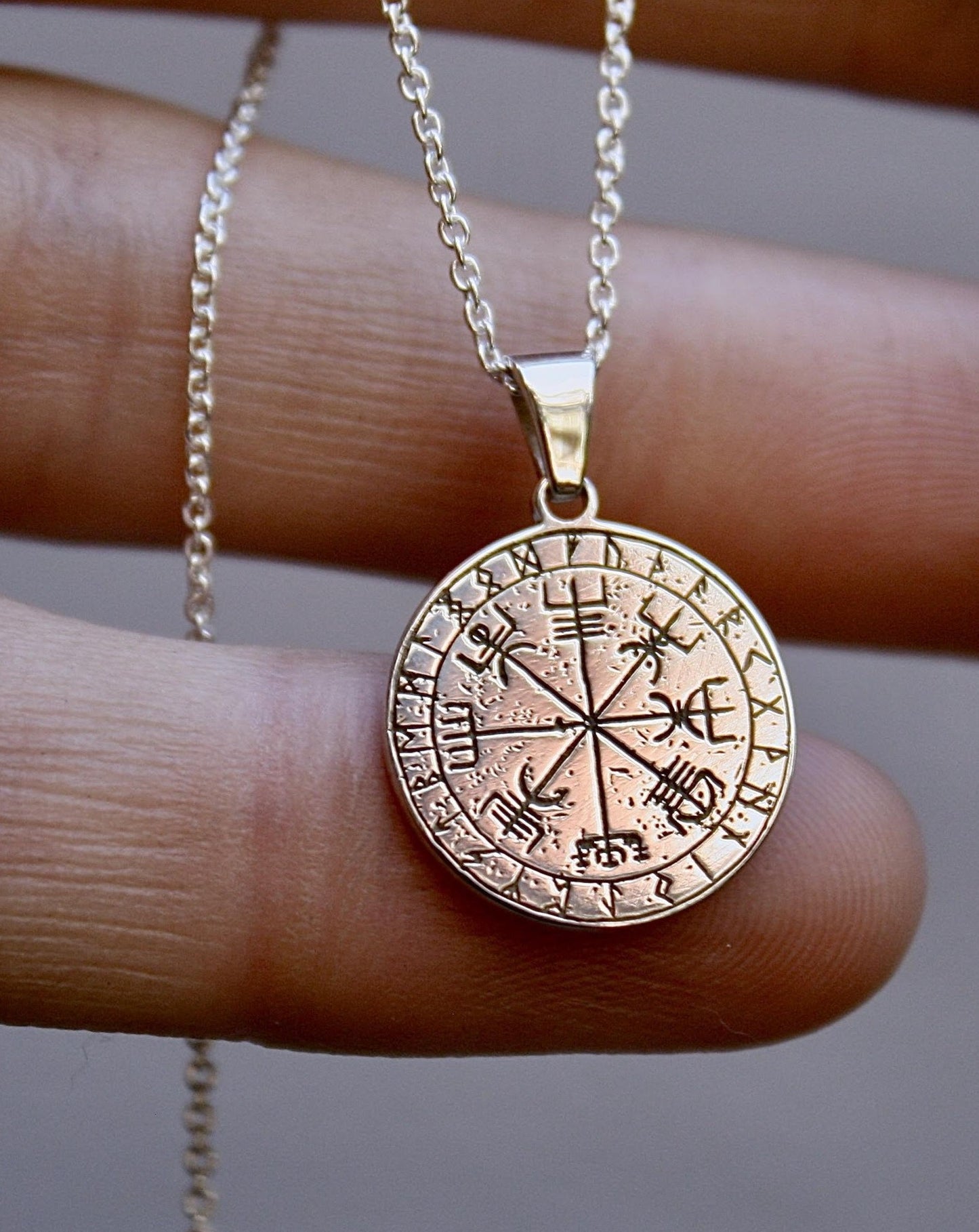 Nordic Compass Necklace by Jade Rabbit Jewellery. Shown close up in hand.