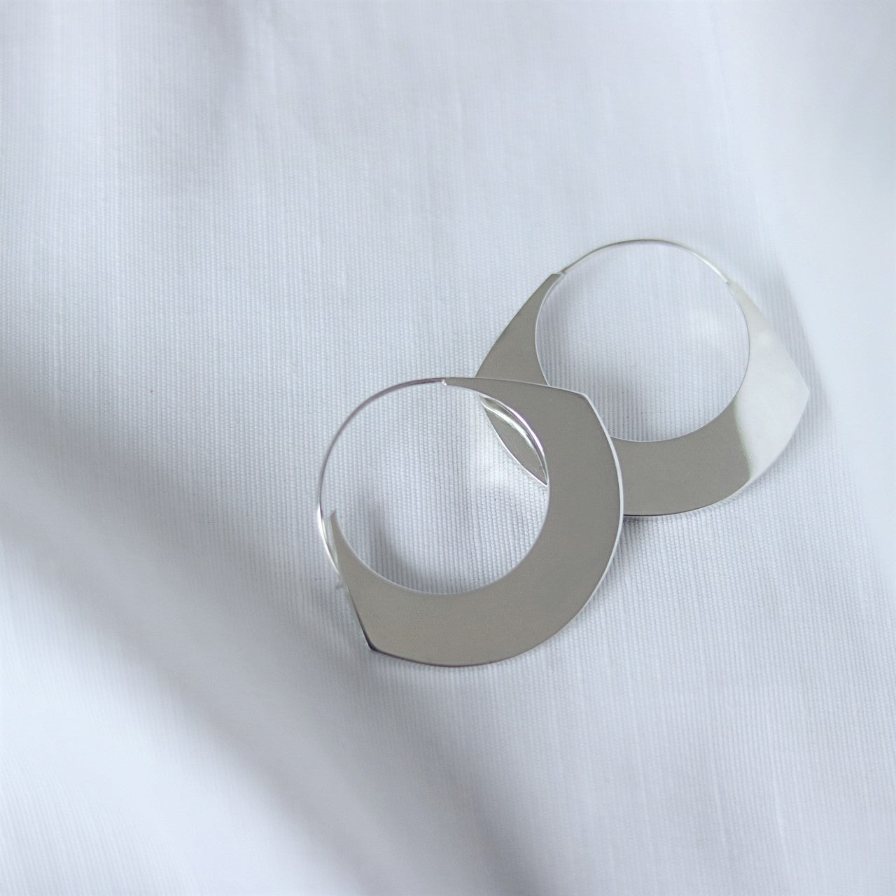 Sterling silver statement earrings on white linen background