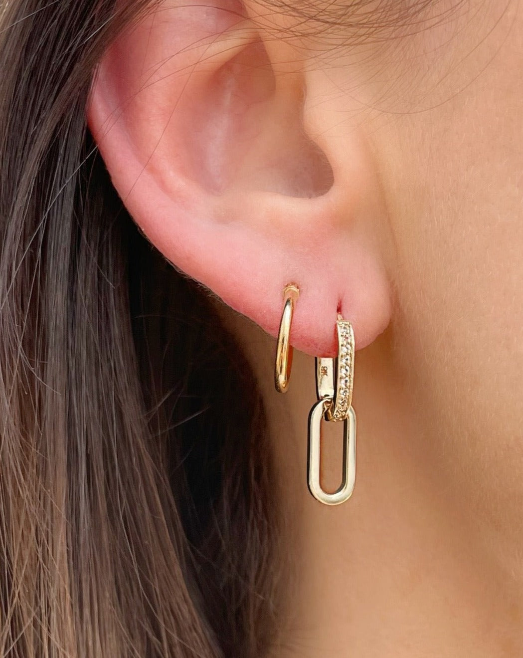 Gold and sapphire hoop earrings on female ear